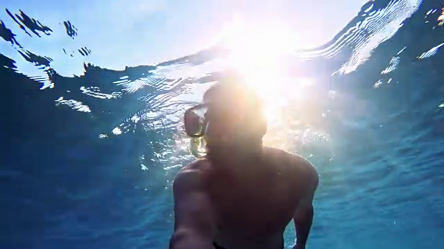 一个年轻人在潜水，阳光照耀着海面视频素材