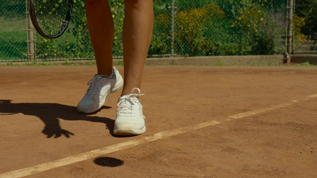 慢镜头近距离的女人的白色运动鞋和摄像机平移，因为她准备发球视频素材