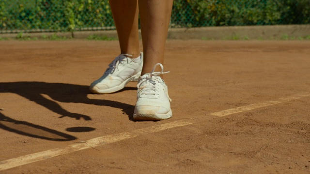慢镜头近距离的女人的白色运动鞋和摄像机平移，因为她准备发球视频素材