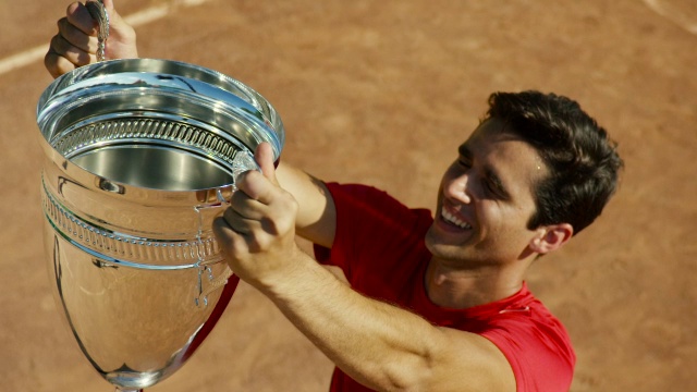 男子在红土球场举起网球奖杯的慢镜头视频素材