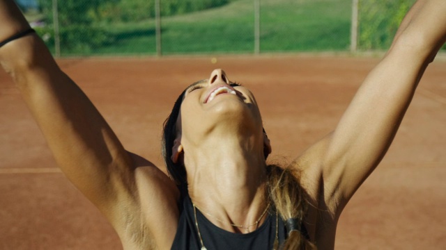 慢镜头近距离女子举起她的手臂在红土网球场胜利的V视频素材