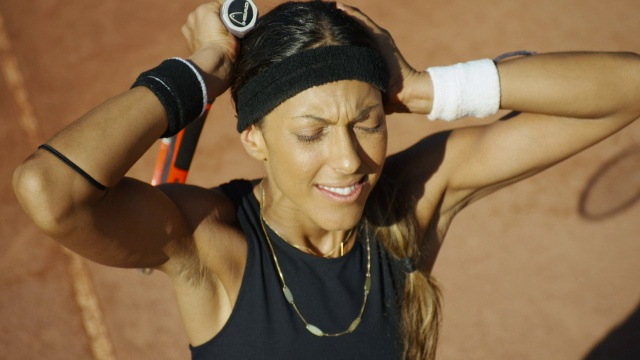 在红土网球场上庆祝的微笑女子的近距离慢动作头顶镜头视频素材