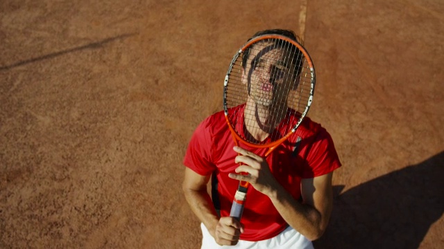头顶红土场上男子亲吻网球拍的慢镜头视频素材