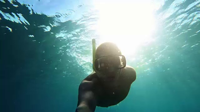 年轻男子戴着浮潜面罩潜水视频素材