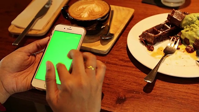 在咖啡店用绿屏手机的女人视频素材