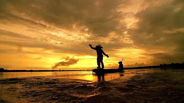 清晨日出前，亚洲渔民在木船上撒网捕鱼视频素材