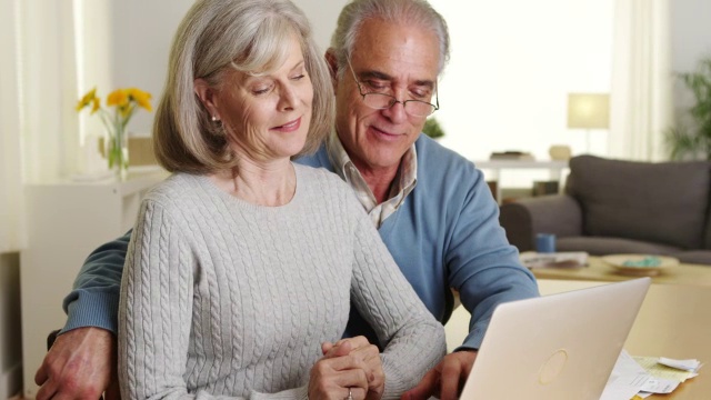 快乐的老年夫妇用笔记本电脑支付账单视频下载