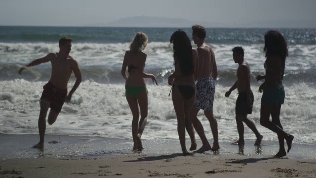 精力充沛的一群年轻的跨种族朋友在海滩上玩视频下载