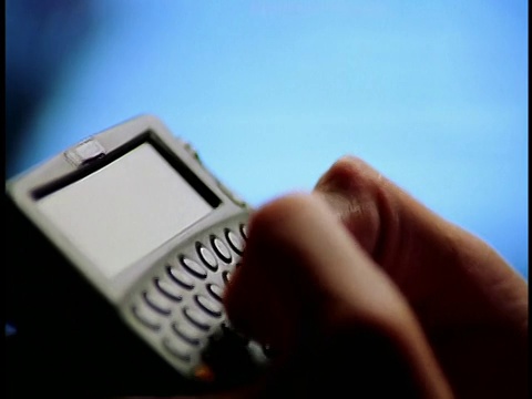 极端近的侧视图男性手指打字在无线互联网设备(PDA)与蓝色背景视频素材