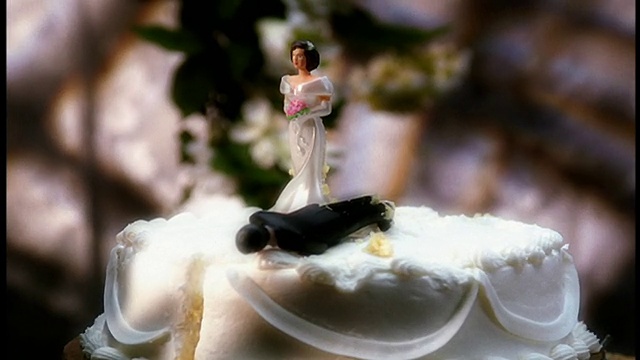 近距离放大，链锯切割婚礼蛋糕与微型塑料新娘和新郎视频下载