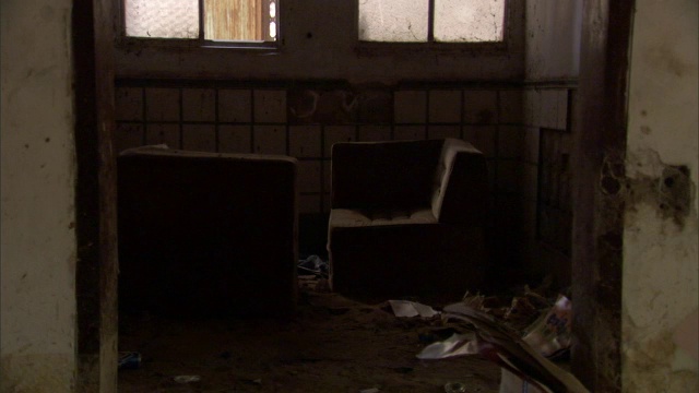 在一间被洪水破坏的房间里，移位的家具和碎片散落在地板上。视频下载
