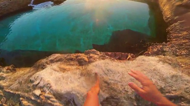从个人的角度，在夏季日出的地中海科斯塔布拉瓦海岸线跳入一个天然游泳池的家伙的慢动作的观点。视频素材