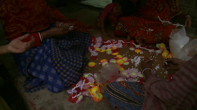 这是三个印度妇女制作花卉项链的特写。视频素材