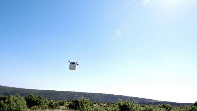 阳光下，无人机载着一个箱子飞过群山视频下载