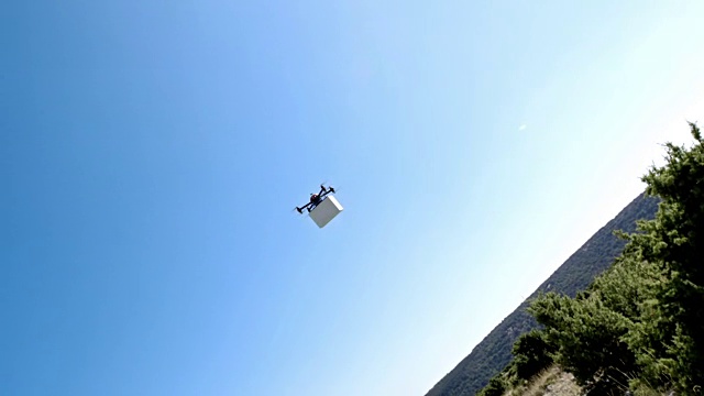 无人机在阳光充足的山丘上运送一个箱子视频素材