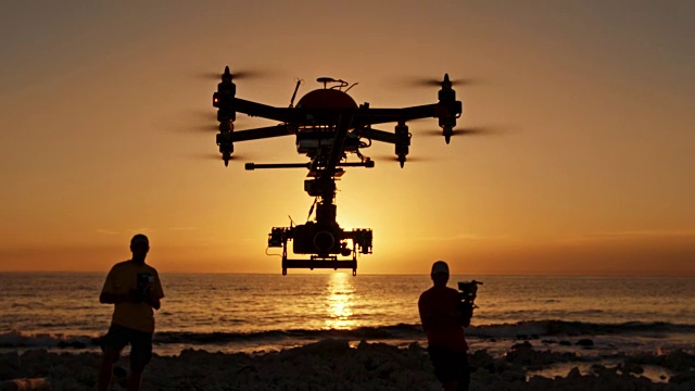 两名男性操作员在日落时分操控无人机视频下载