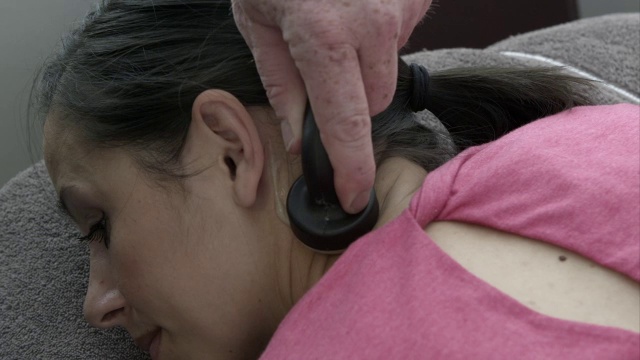 治疗师用按摩器按摩女人的脖子。视频素材
