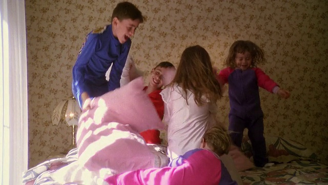 一群孩子在床上打枕头仗视频素材