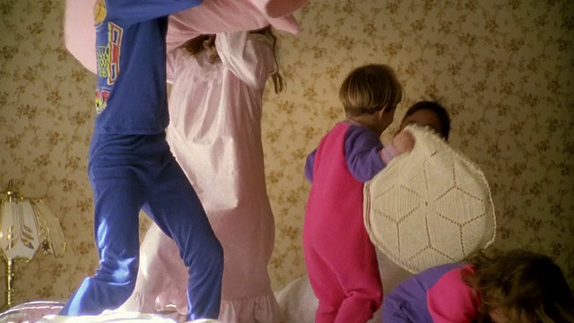 一群孩子在床上打枕头仗视频素材