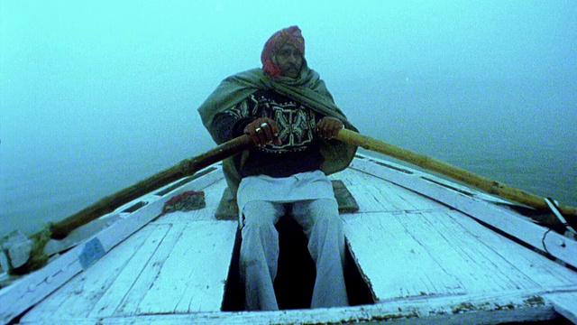 慢动作船的观点，中年男子划船在恒河上的薄雾在黄昏/瓦拉纳西，印度视频下载