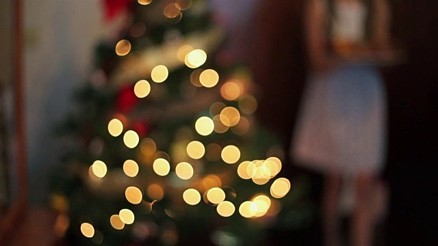 年轻的女孩带着圣诞糖果在圣诞树旁。视频素材