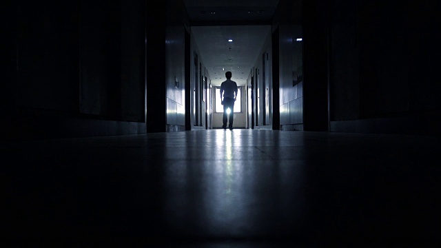 男人走在黑色的走廊里视频素材