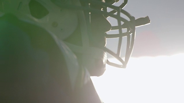 CU SLO MO.职业足球运动员在比赛头盔的剪影由体育场灯光。视频下载