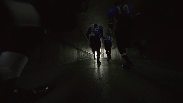 在比赛日，职业足球运动员跑过体育场隧道时，低角度摄影。视频下载