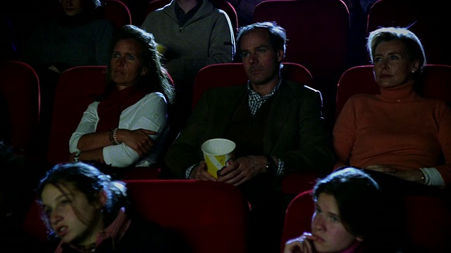 中镜头摄影车拍摄过去的观众看电影在电影院看起来严肃视频下载