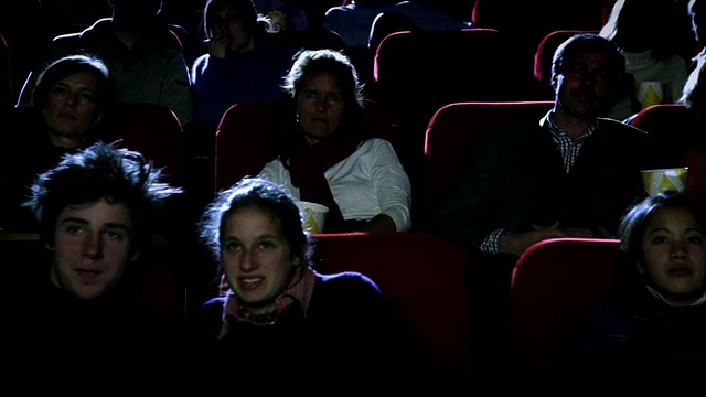 中景摄影车在影院里经过专心观看电影的观众视频下载