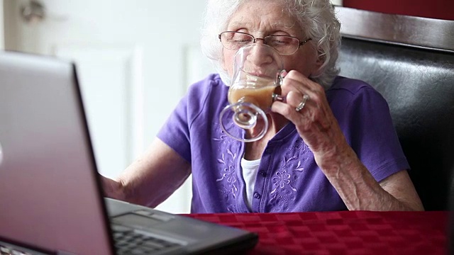高级女性使用笔记本电脑和喝茶视频下载