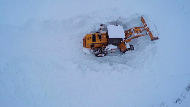 傍晚扫雪机清理积雪道路的鸟瞰图。视频下载