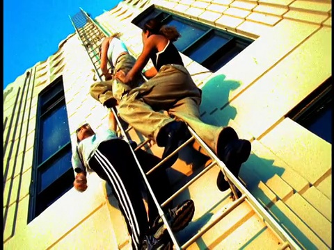 低角度缩小三个年轻人挂在梯子上的建筑/洛杉矶，加利福尼亚视频下载