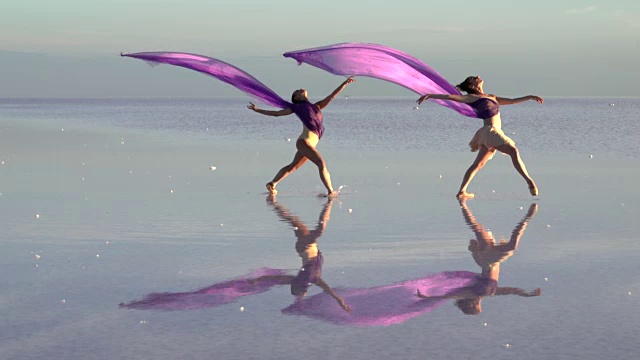 年轻的芭蕾舞者在盐湖上用彩色薄纱跳舞视频下载