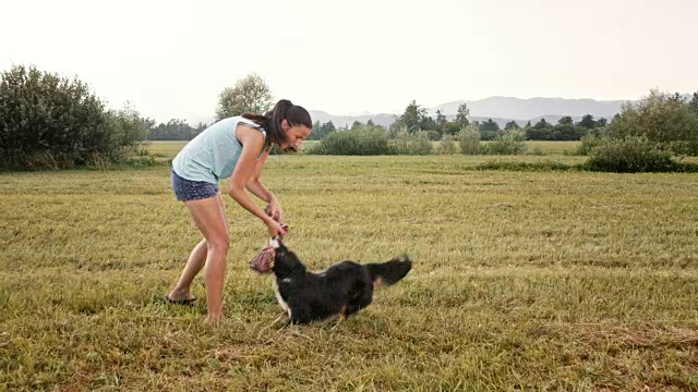 一名年轻女子和她的边境牧羊犬在外面拉绳子视频素材