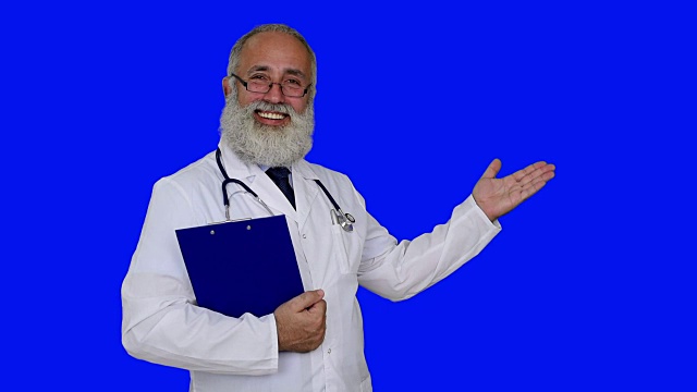 成年资深医生展示拷贝空间和微笑在一个蓝色的背景视频下载