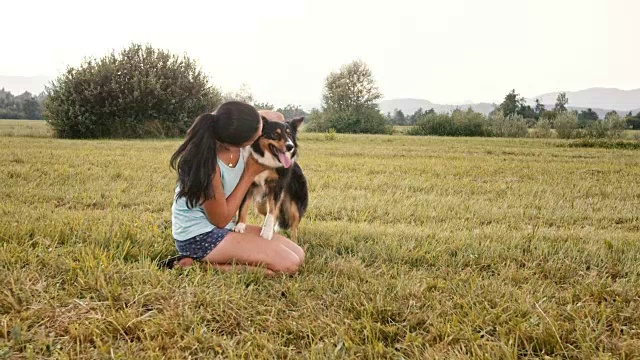 年轻女子在草地上抱着她的狗视频素材