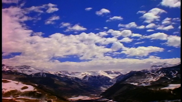 宽镜头延时云在蓝色的天空滚动在积雪覆盖的落基山脉/附近特柳赖德，科罗拉多州视频素材
