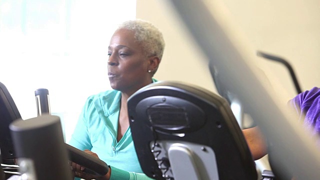 高级非洲裔美国妇女在健身房锻炼自行车视频素材