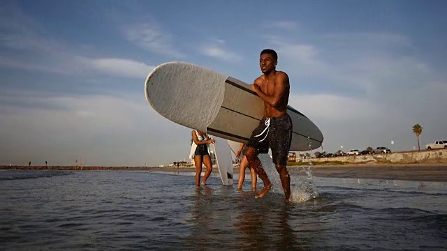 年轻的非洲裔美国男性冲浪者与冲浪板冲入水中视频下载