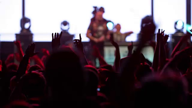 在晚上的音乐会上，人们举起手跳起来视频素材