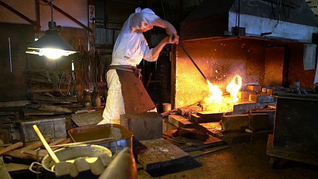 铁匠从熔炉中取出金属，用锤子把它打成型视频素材