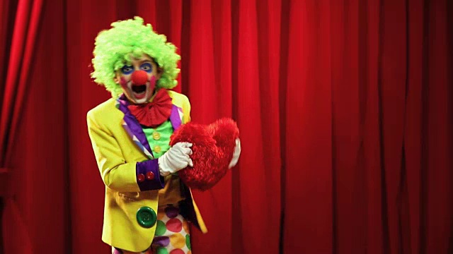 在一年一度的节日里，男孩穿着小丑服装，带着毛绒玩具在舞台上表演视频素材