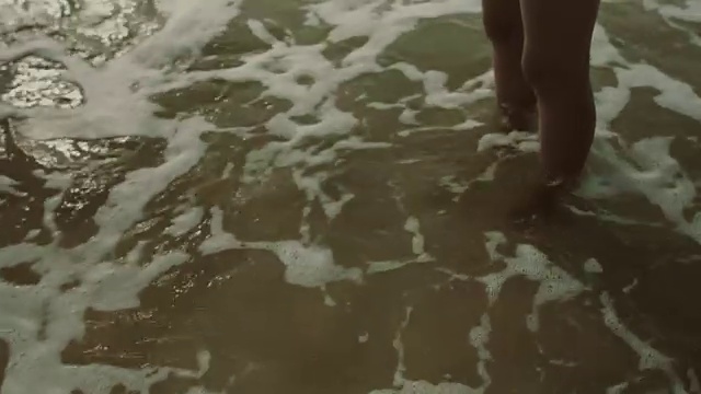 肖像美丽的女人在比基尼站在大西洋海滩在法国南部的脚在水视频下载