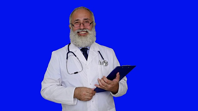 成年资深医生在蓝色背景的写字板上写字。视频下载