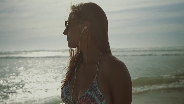 在法国南部荒凉的海滩上听音乐的美丽女人的肖像视频下载