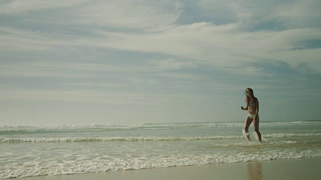 在法国南部荒凉的大西洋海滩上，穿着比基尼的美丽女子散步、跳舞、听音乐视频下载