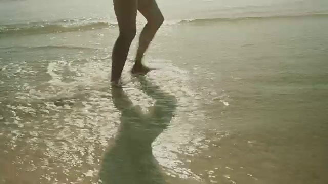 在法国南部的大西洋海滩上，穿着比基尼的美女在水中行走视频下载