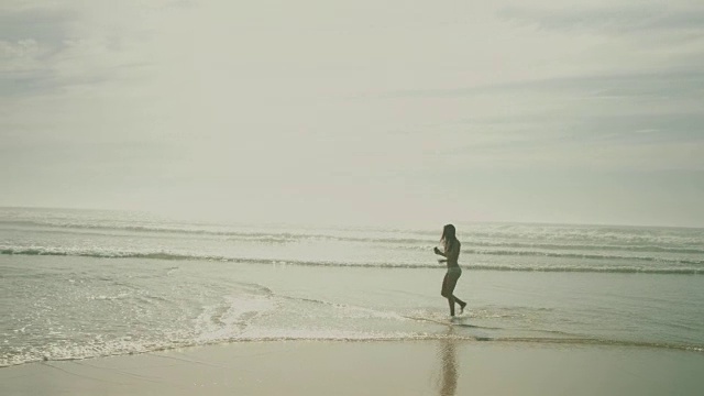 在法国南部的大西洋海滩，穿着比基尼的美丽女子在水中散步，跳舞，听音乐视频下载