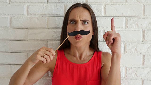 有趣的女人玩纸胡子玩得很开心视频下载